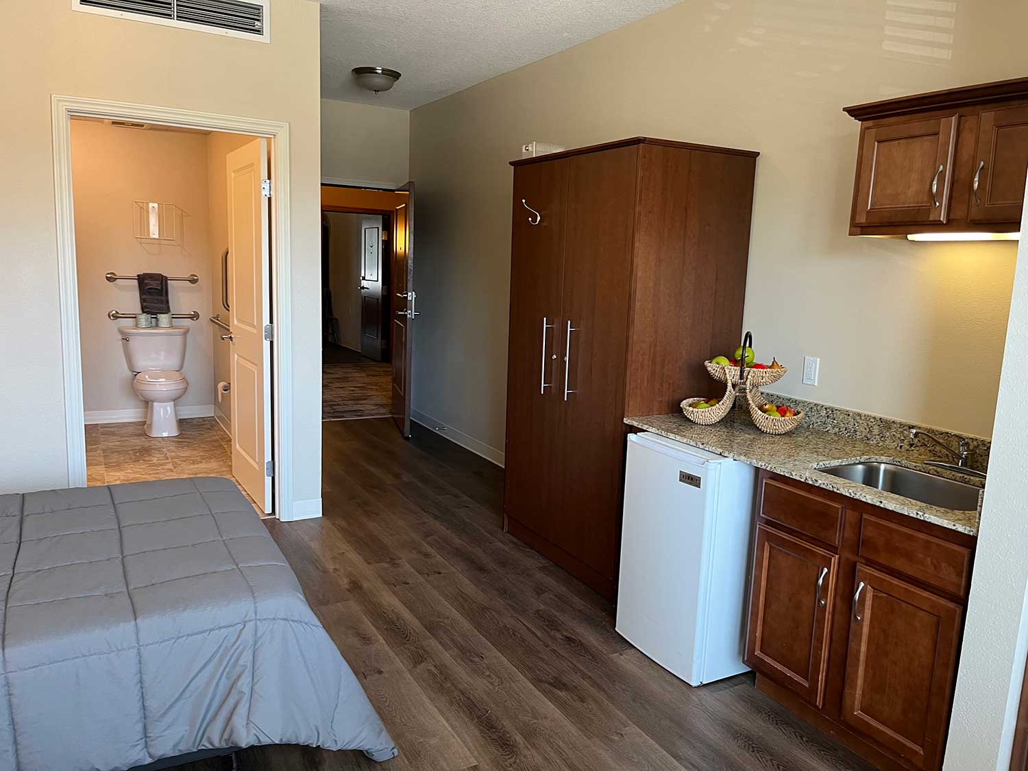 The Rosemount, care suites view with kitchenette, entry, and bath, modern and elegant styling, variety of wood and tile, pleasant interior decor